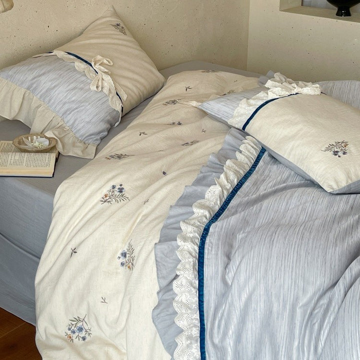 Romantic cotton satin bedding set with ruffles, embroidered flower bouquets, and decorative rolls Stornfield