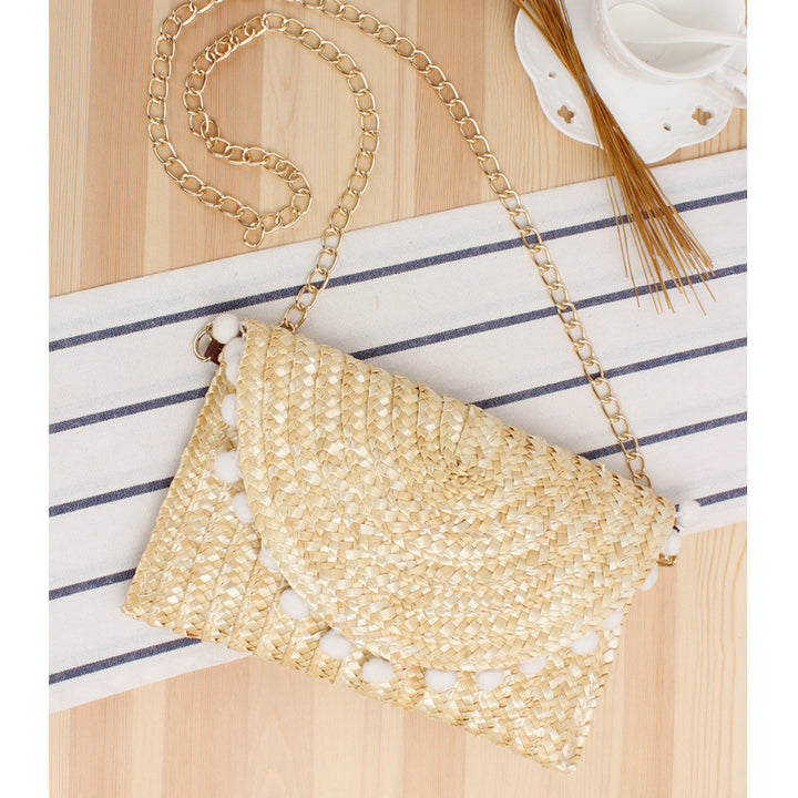 Clutch made of handwoven natural material with decorative pompons Stornfield