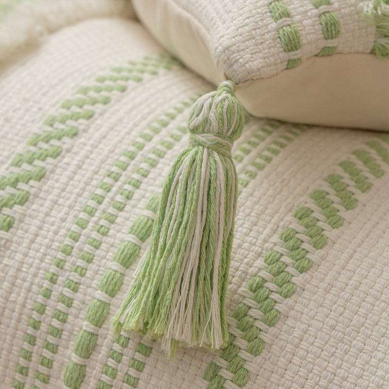 Square decorative cushion with boucle stripes, woven texture, and corner tassels