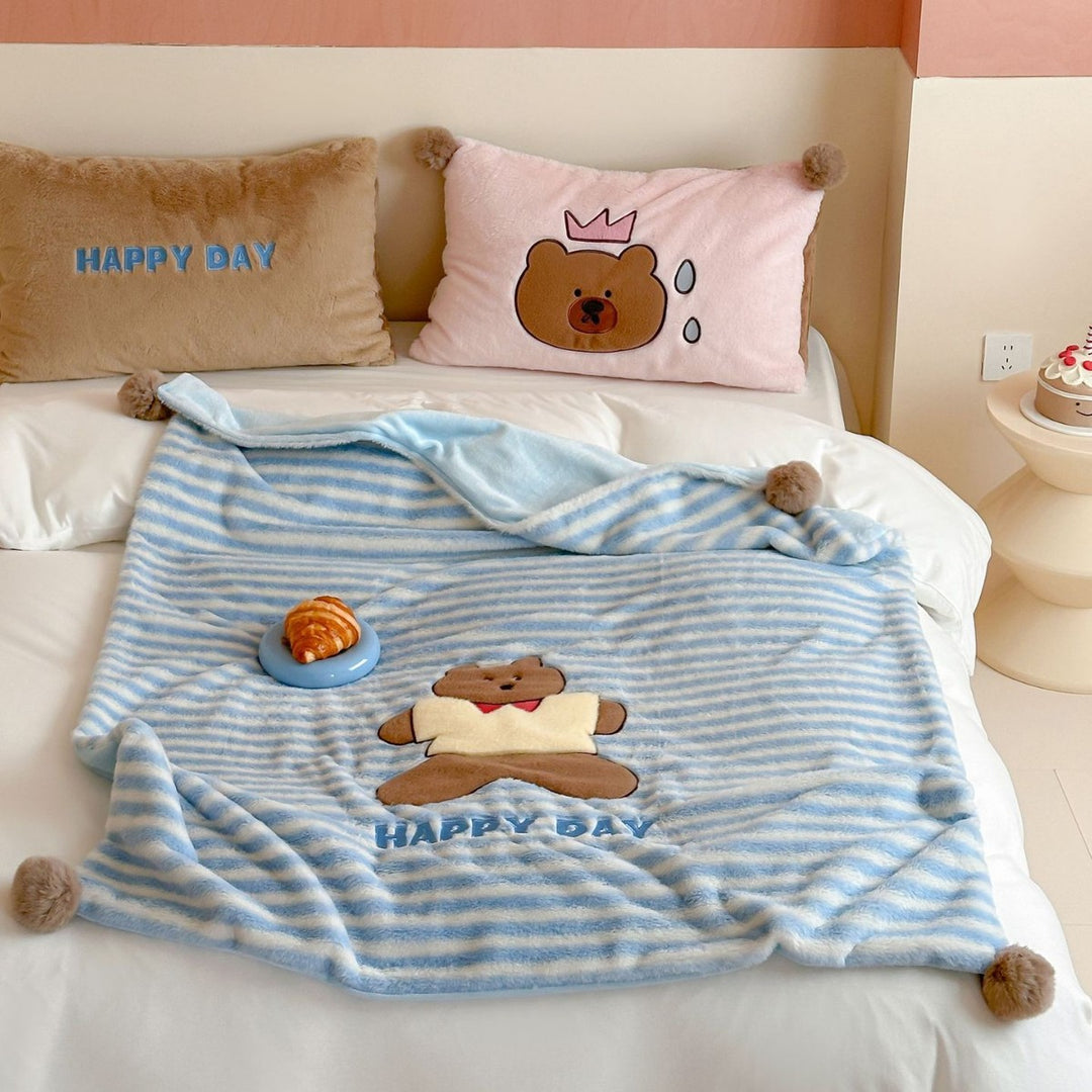 Plush cuddle blanket with striped texture, pom-pom corners & embroidered bear motif