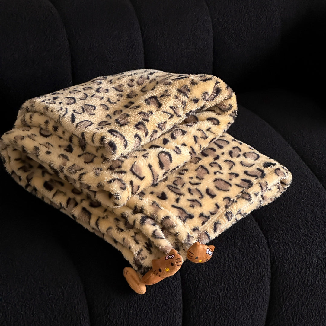 Cozy throw blanket made of microfleece with leopard print and plush pendants