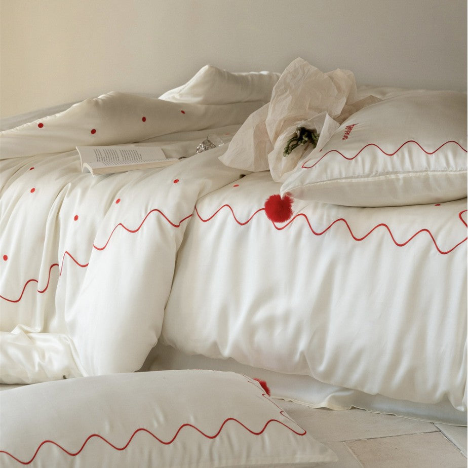 Bedding set made of cotton satin with wavy embroidery edge and pompom cushion
