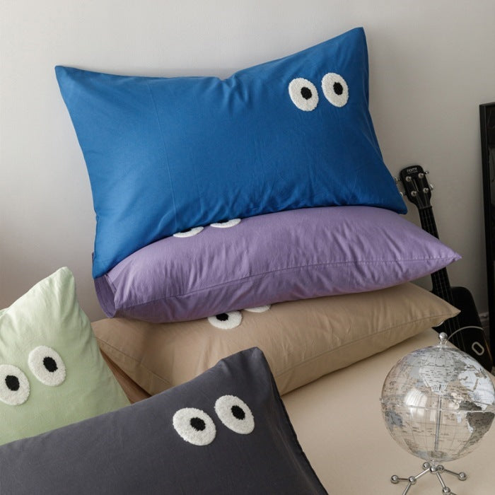 Playful cushion cover set with embroidered eye appliqués made of soft cotton fabric