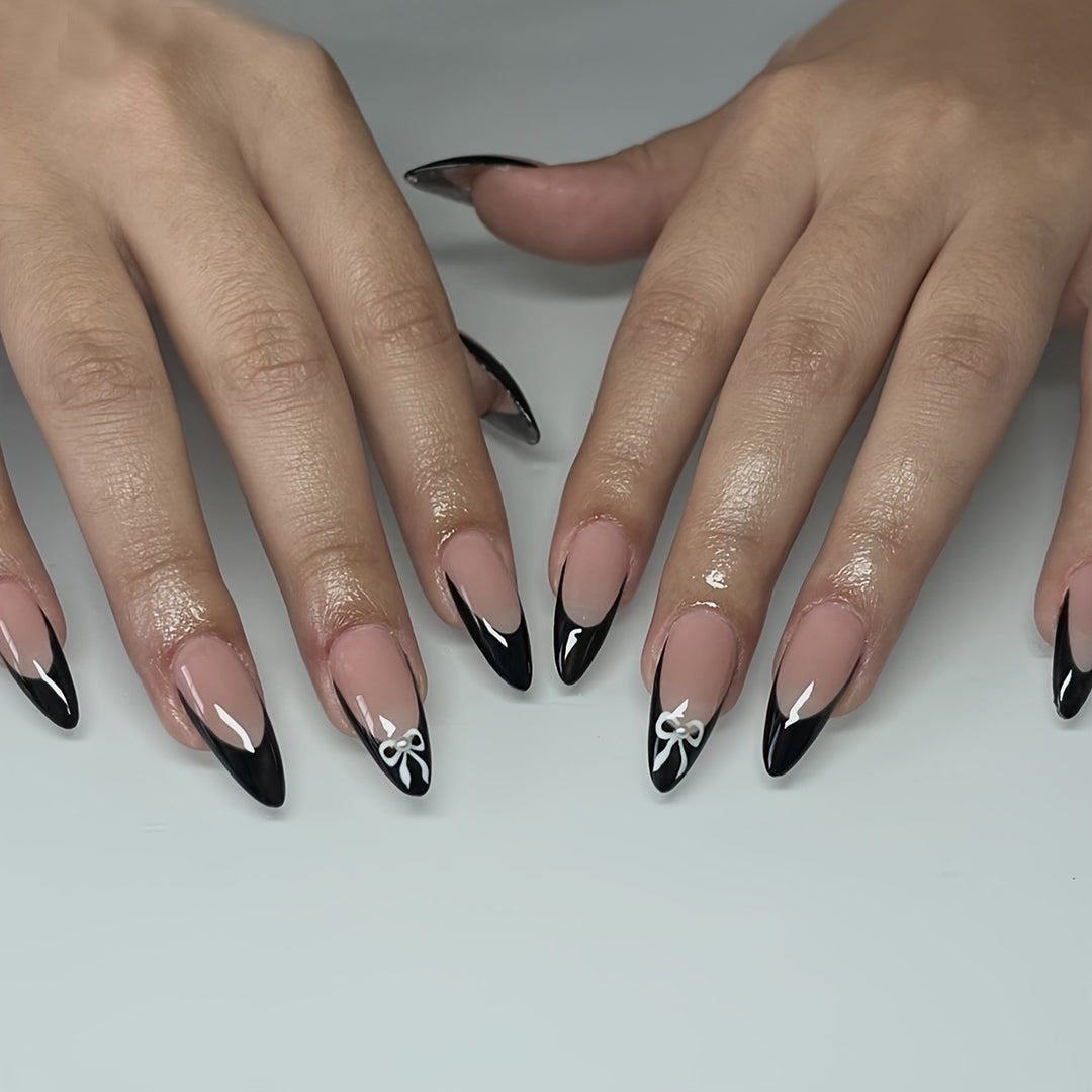 Acrylic nail set with elegant black and white design and cute bow accents Stornfield