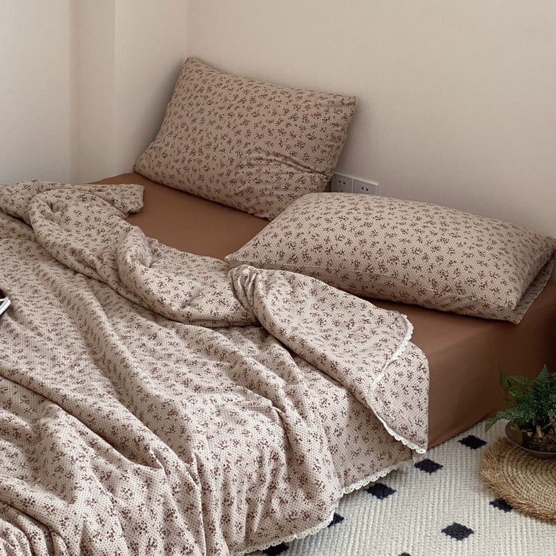 Quilted throw blanket made of cotton blend with delicate floral pattern and lace edge