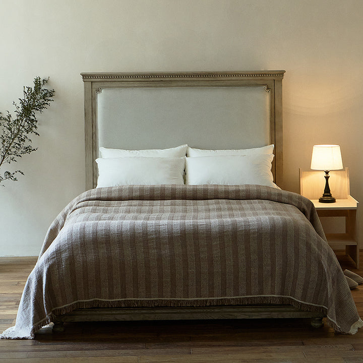 Massive wooden bed with upright slatted headboard and natural linen bedding