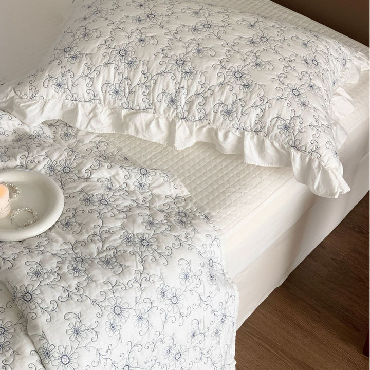 Padded quilted bedspread with a floral all-over pattern and ruffled edges