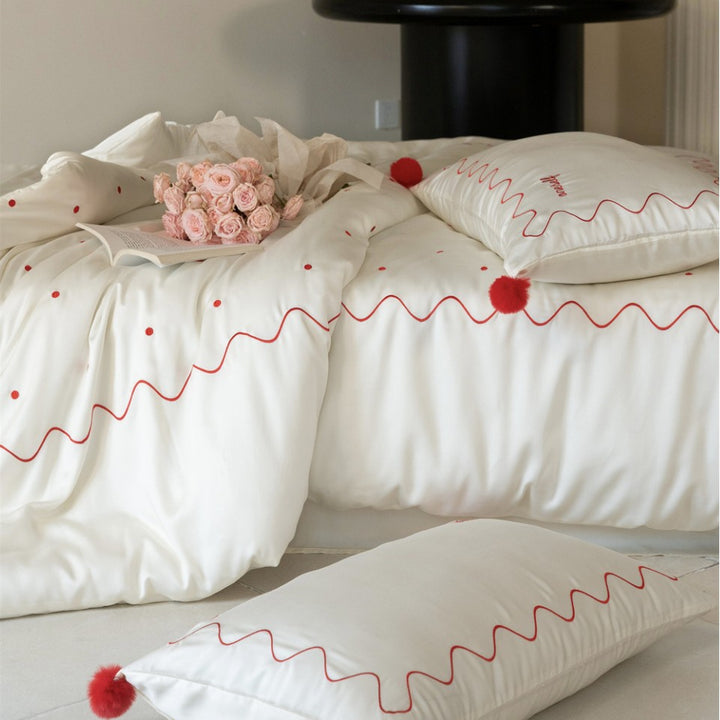 Bedding set made of cotton satin with wavy embroidery edge and pompom cushion