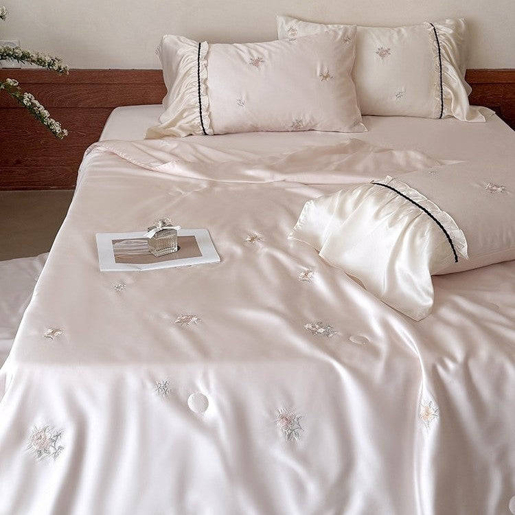 Exquisite satin bedding set with floral embroidery, gathered pillow shams, and contrasting piping