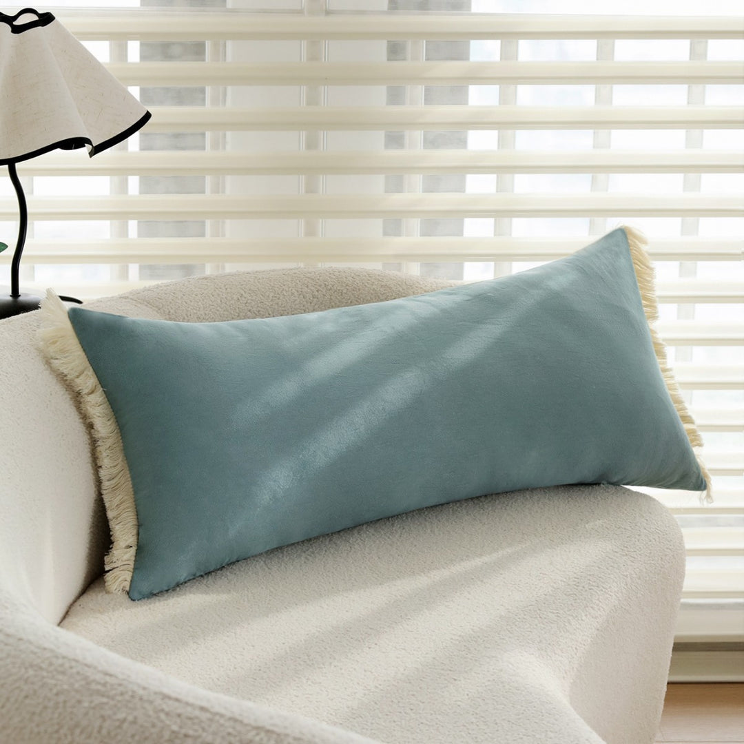 elongated decorative cushion with fringes and velvety surface