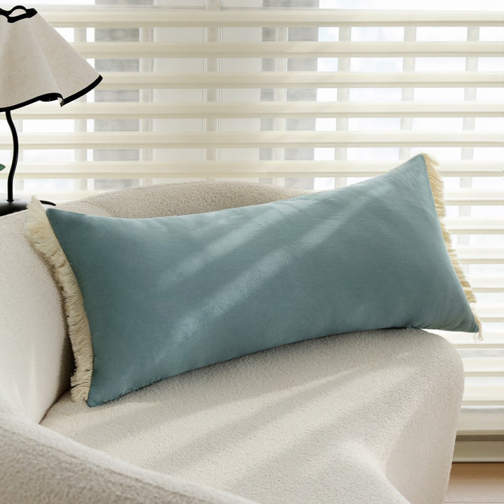 elongated decorative cushion with fringes and velvety surface