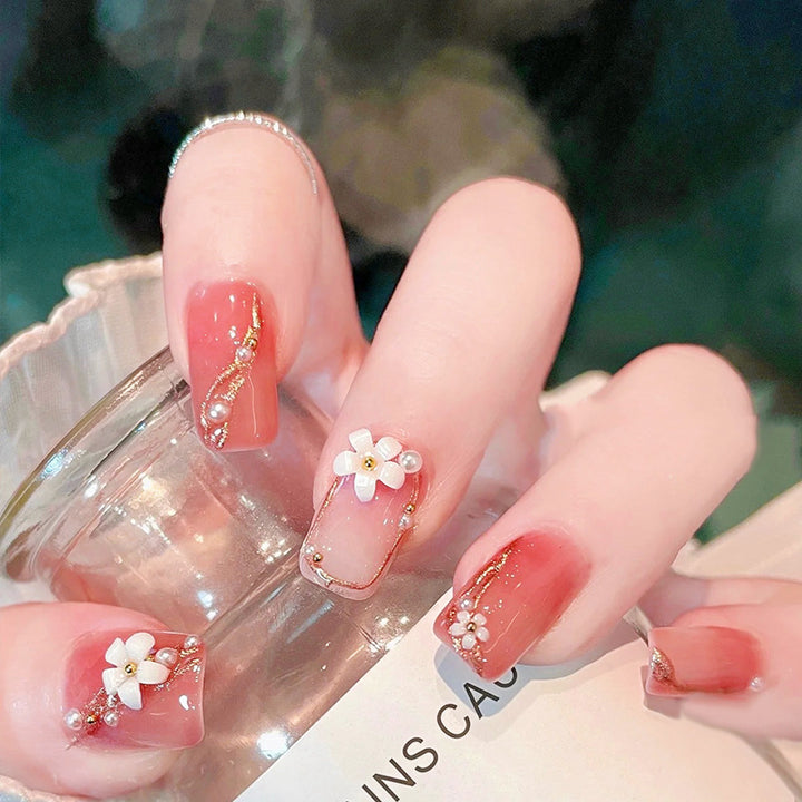 Acrylic nail set with elegant floral decorations and glamorous pearl accents Stornfield