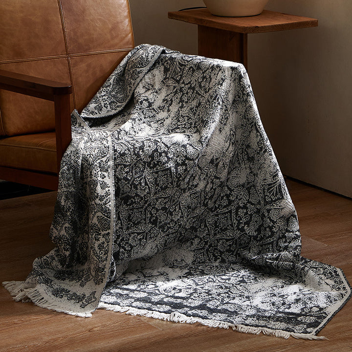 Large cozy living blanket made of cotton blend fabric with geometric jacquard pattern and fringed hem