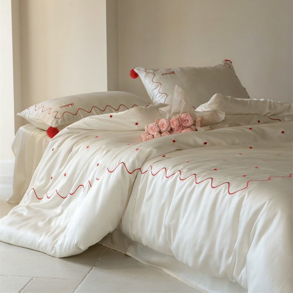 Bedding set made of cotton satin with wavy embroidery edge and pompom cushion