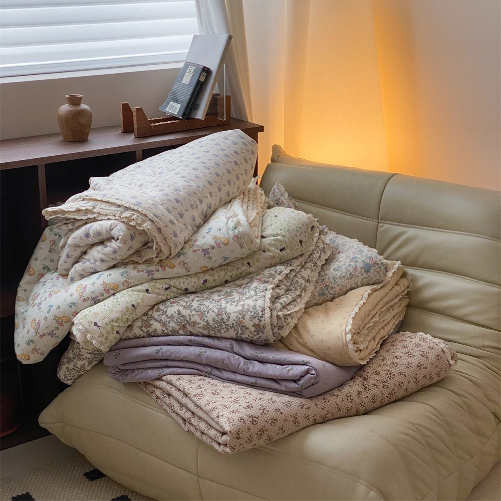Quilted throw blanket made of cotton blend with delicate floral pattern and lace edge