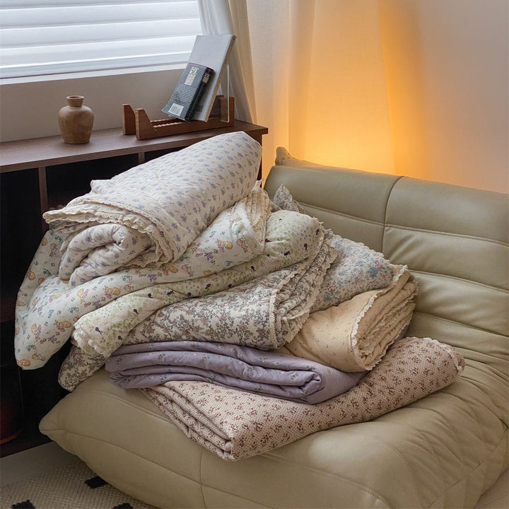 Quilted throw blanket made of cotton blend with delicate floral pattern and lace edge