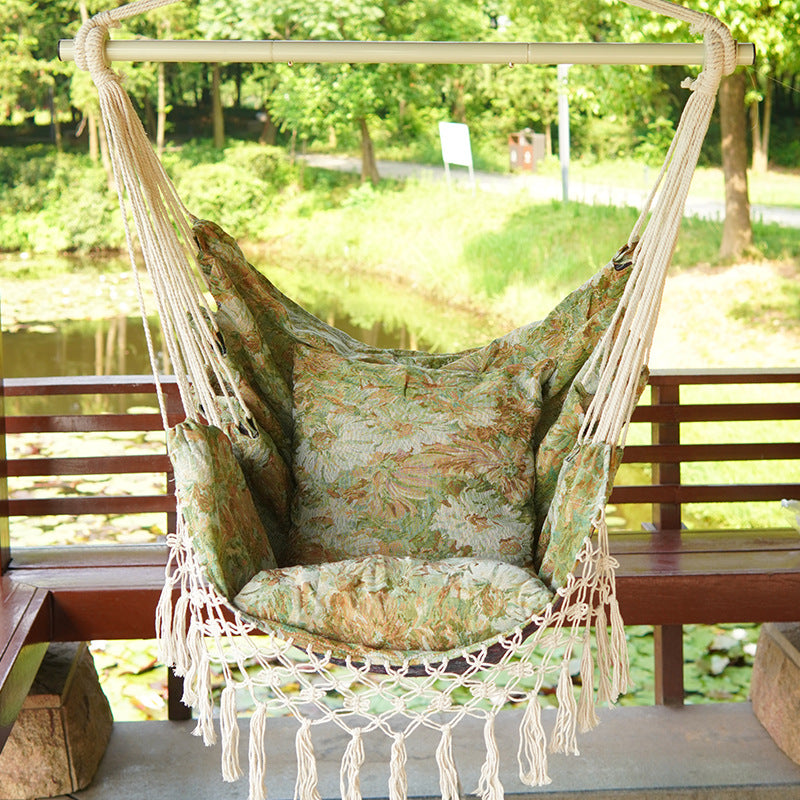 Woven hammock chair with padded floral cushions and macramé fringe Stornfield