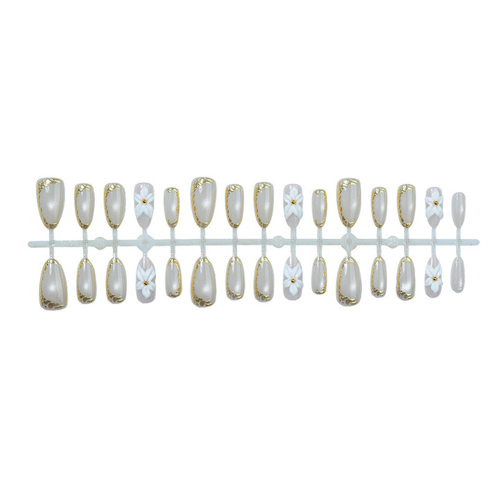 Acrylic nail set with elegant gold embellishments and floral accent Stornfield