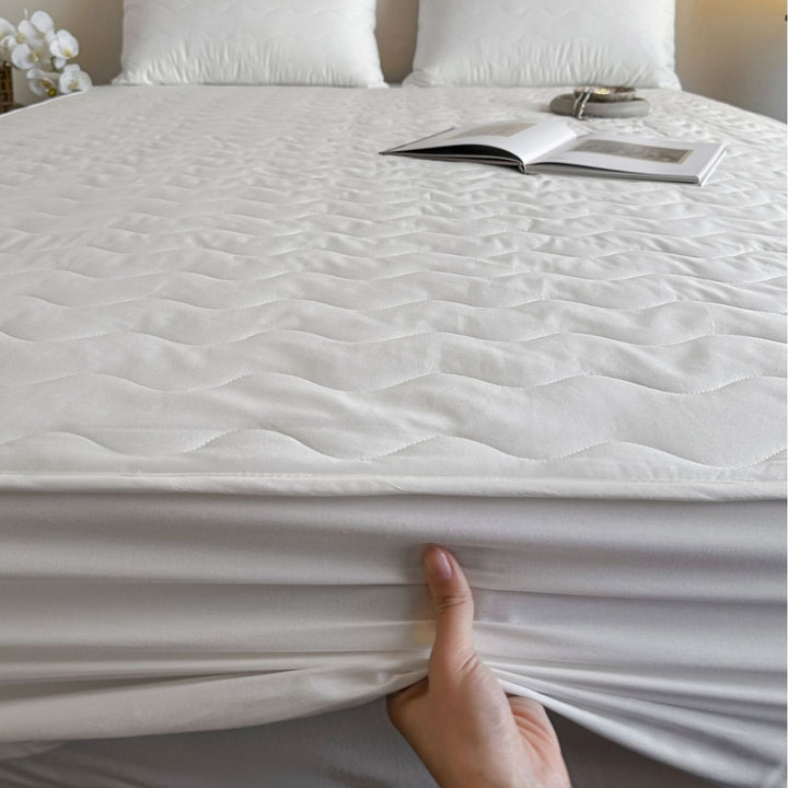 Padded mattress protector with all-round stretch and quilting