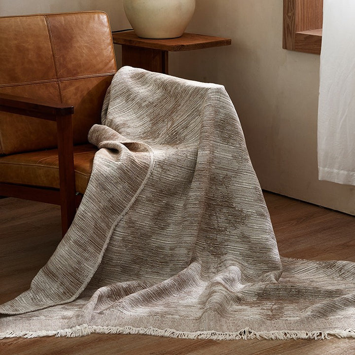 Large cozy living blanket made of cotton blend fabric with geometric jacquard pattern and fringed hem