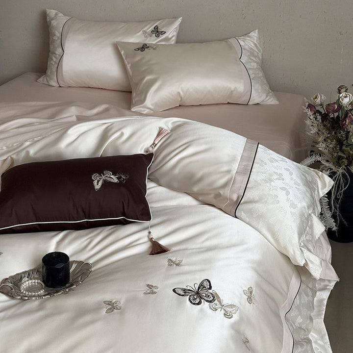 Luxurious satin bedding set with embroidered butterflies, decorative pillows, and tassels