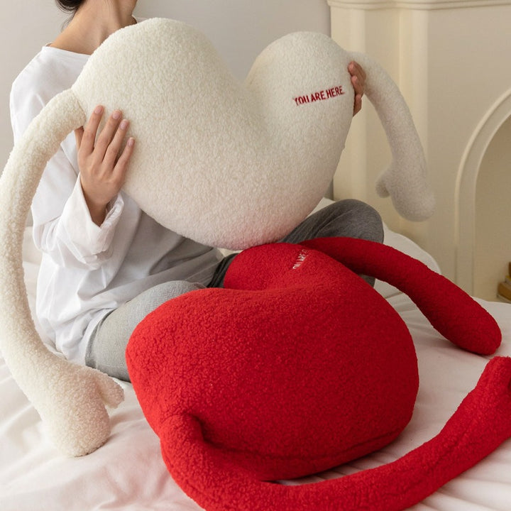 Cuddle pillow in heart shape with extra long arms made of sherpa fleece and embroidery detail