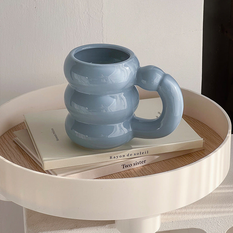 Sculptural ceramic mug with iridescent glaze and curved ring handle