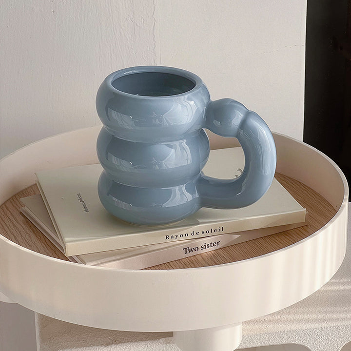 Sculptural ceramic mug with iridescent glaze and curved ring handle