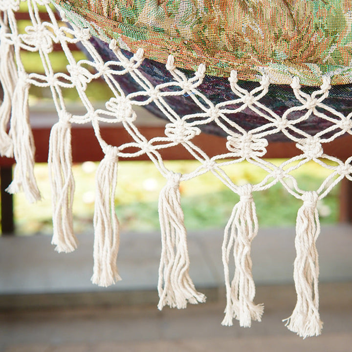 Woven hammock chair with padded floral cushions and macramé fringe Stornfield