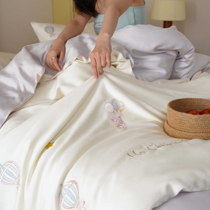 Premium children's bedding set made of cotton satin with pastel-embroidered balloon and carousel motifs.