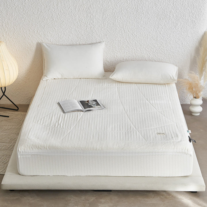 Padded mattress topper with quilted microfiber surface and non-slip fitted edge