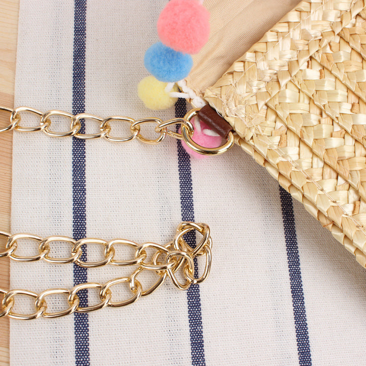 Clutch made of handwoven natural material with decorative pompons Stornfield