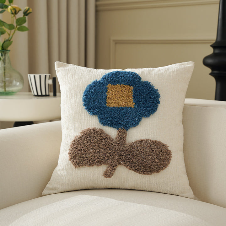 Square decorative pillow with hand-tufted floral appliqué and textured linen look