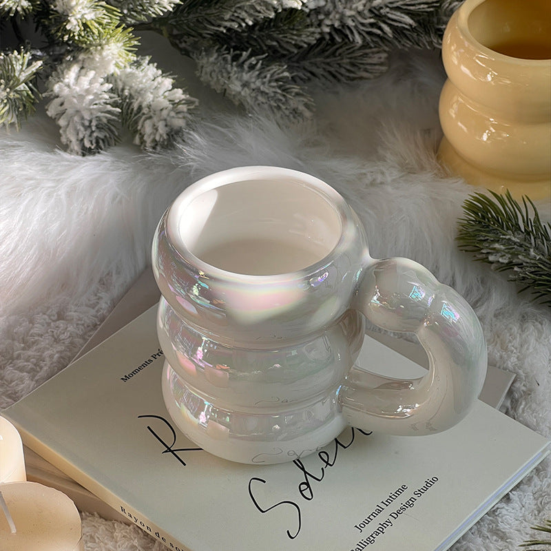 Sculptural ceramic mug with iridescent glaze and curved ring handle
