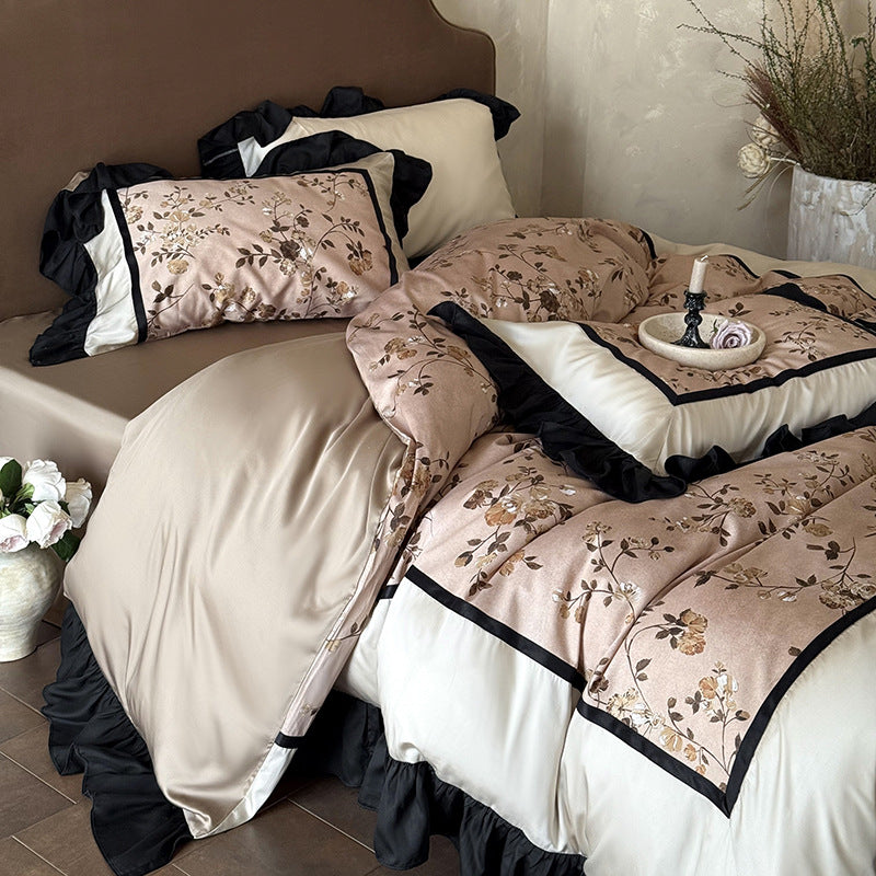 Satin bedding set with embroidered flower appliqués, layered flounce and decorative cushion