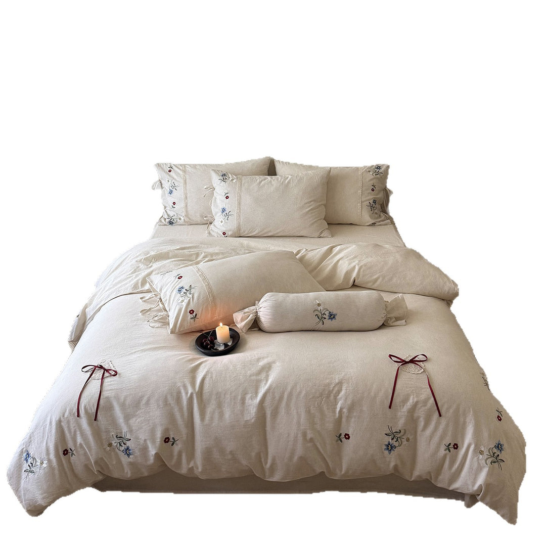 Romantic linen-cotton bedding set with delicate floral embroidery, tie loops and round cushion