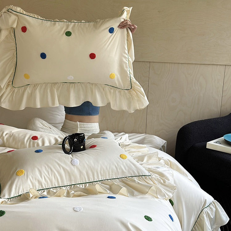 Bedding set with embroidered dots, decorative ruffles, and fine piping