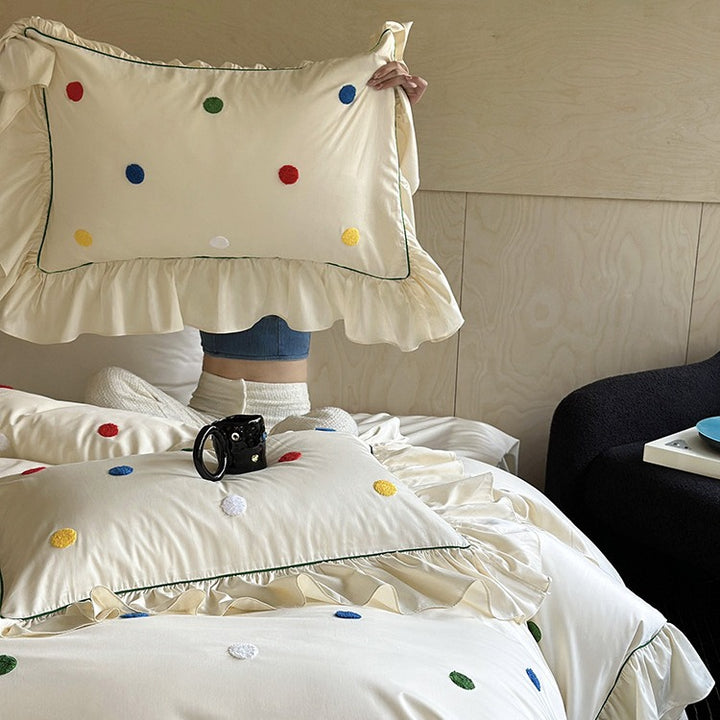 Bedding set with embroidered dots, decorative ruffles, and fine piping