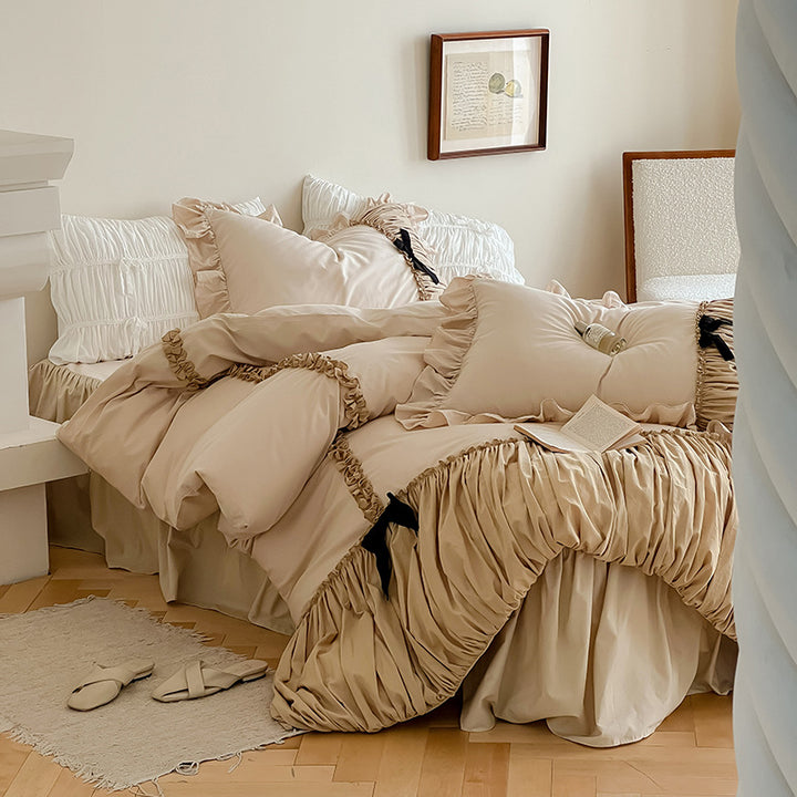 Luxurious satin bedding set with gathered ruffle, braided decorative ribbons and bow appliqué