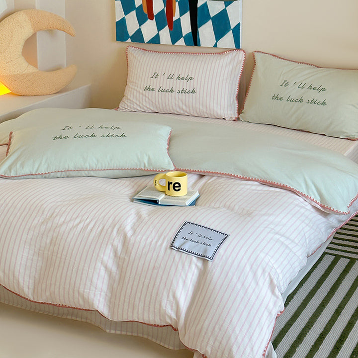 Striped cotton bedding set with subtle slogan appliqués and decorative piping