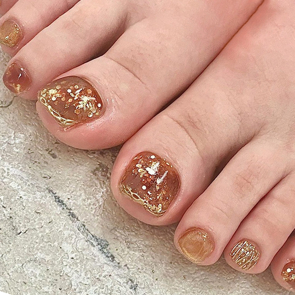 Artistic toenail design with glitter and golden accents Stornfield