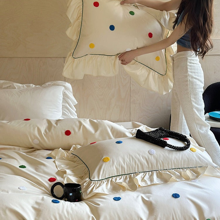 Bedding set with embroidered dots, decorative ruffles, and fine piping