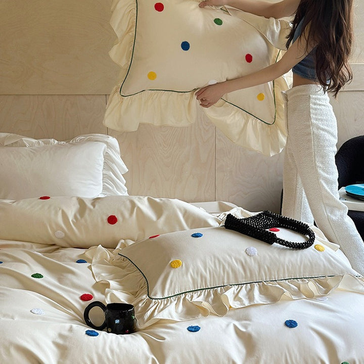 Bedding set with embroidered dots, decorative ruffles, and fine piping