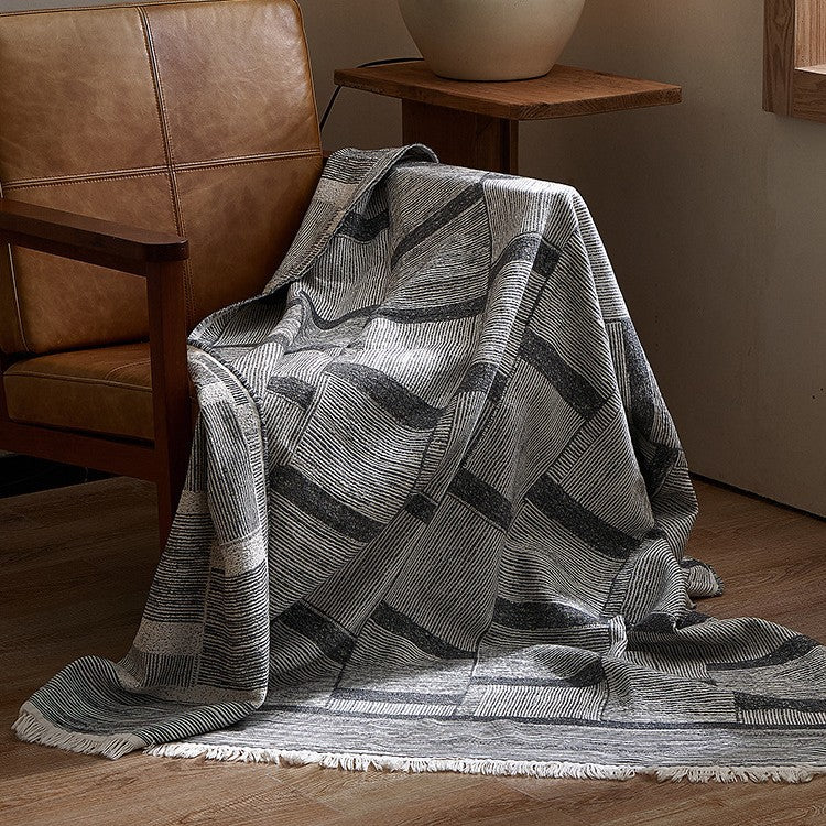 Large cozy living blanket made of cotton blend fabric with geometric jacquard pattern and fringed hem