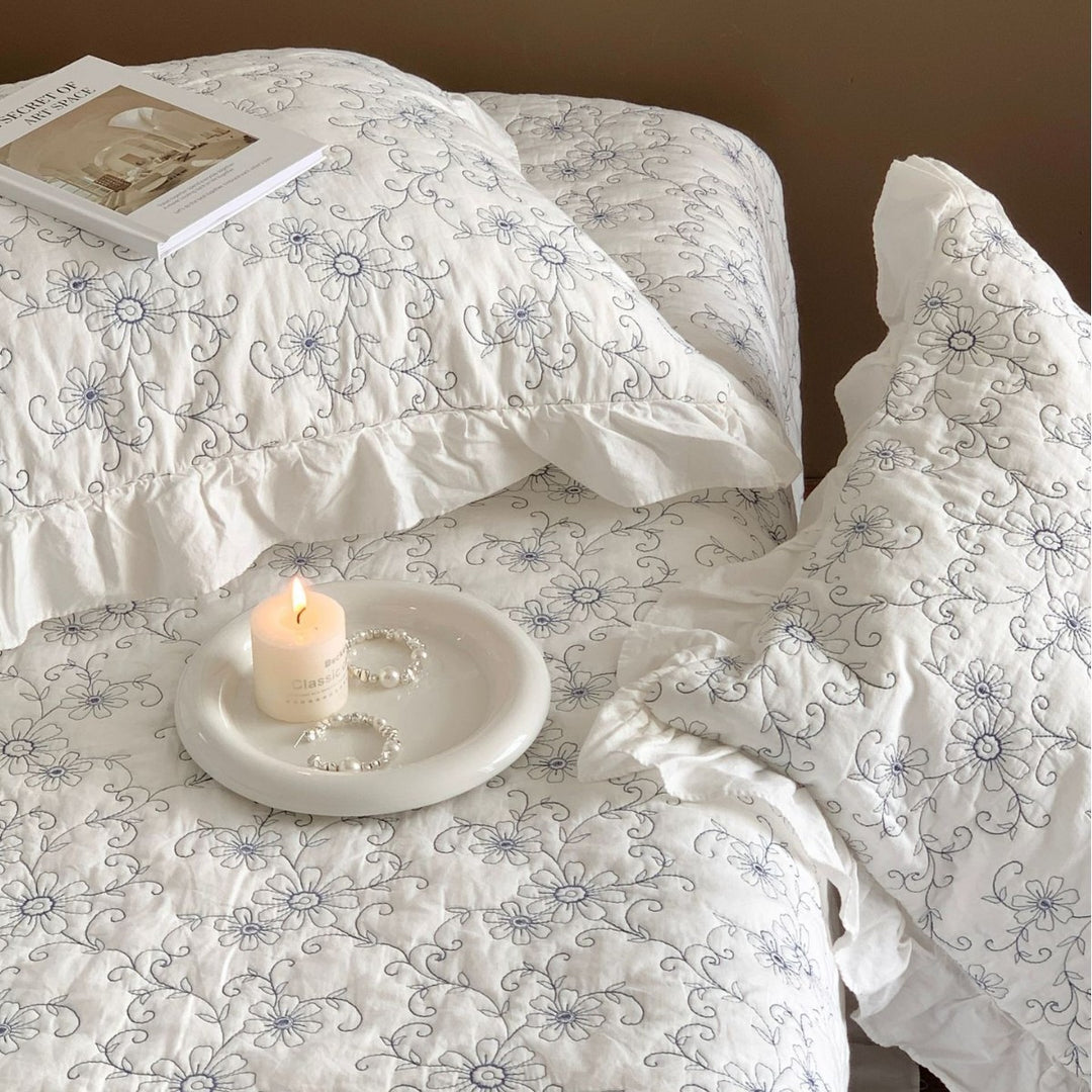 Padded quilted bedspread with a floral all-over pattern and ruffled edges