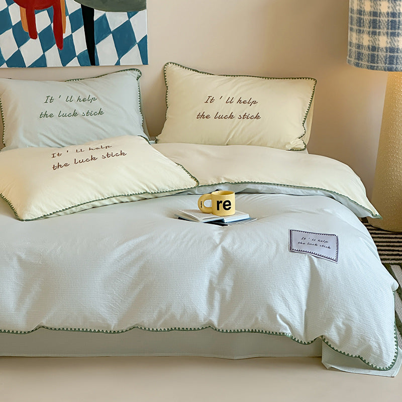 Striped cotton bedding set with subtle slogan appliqués and decorative piping