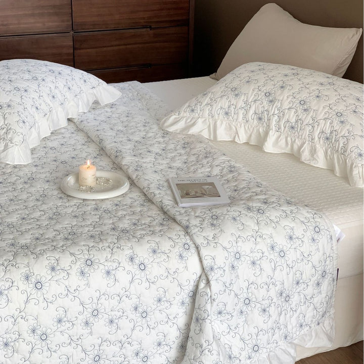 Padded quilted bedspread with a floral all-over pattern and ruffled edges