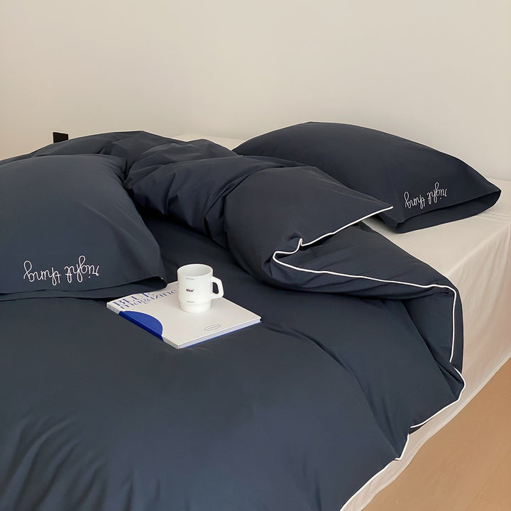 Cotton satin bed linen set with contrasting piping and subtle brand embroidery