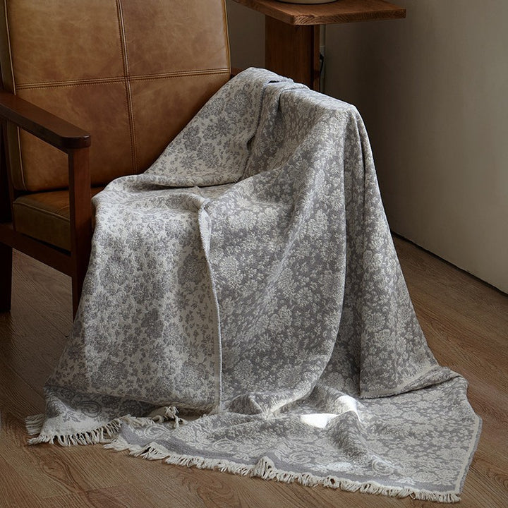 Large cozy living blanket made of cotton blend fabric with geometric jacquard pattern and fringed hem