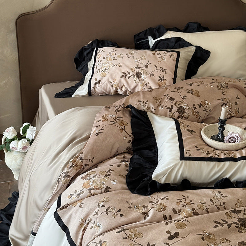 Satin bedding set with embroidered flower appliqués, layered flounce and decorative cushion
